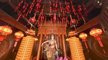 Huzurlu bir tapınak sunağı, bir Bodhisattva heykeli, kırmızı fenerler, altın sütunlar ve çiçeklerle birlikte barış ve bağlılık yayar. 