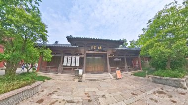 Geleneksel Çin tapınağı, kırmızı fenerler, taş tütsü yakıcı, ve hat plaketi, parlak mavi gökyüzünün altında yeşilliklerle çevrili.. 