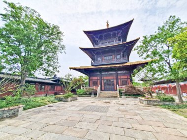 Geleneksel çok katmanlı Çin pagodası verimli yeşilliklerin arasında zarif bir şekilde duruyor. Büyük ahşap girişine doğru taş adımlar atıyor.. 