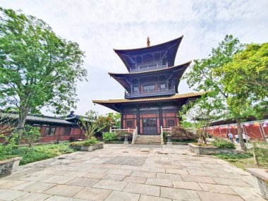 Geleneksel çok katmanlı Çin pagodası verimli yeşilliklerin arasında zarif bir şekilde duruyor. Büyük ahşap girişine doğru taş adımlar atıyor.. 