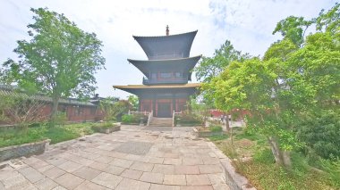 Geleneksel çok katmanlı Çin pagodası verimli yeşilliklerin arasında zarif bir şekilde duruyor. Büyük ahşap girişine doğru taş adımlar atıyor.. 