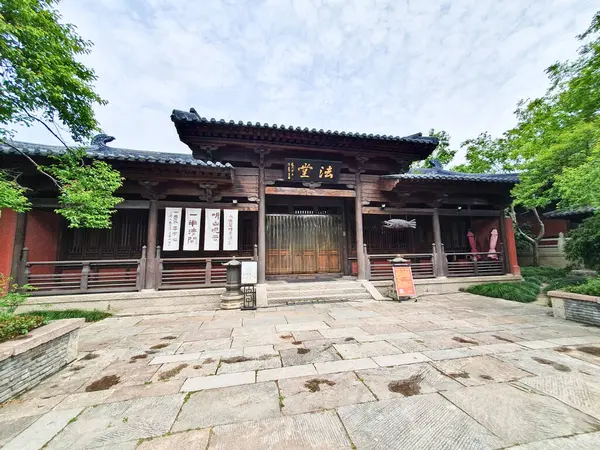 Geleneksel Çin tapınağı, kırmızı fenerler, taş tütsü yakıcı, ve hat plaketi, parlak mavi gökyüzünün altında yeşilliklerle çevrili.. 