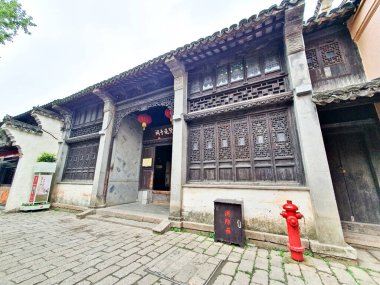 Karmaşık kafes pencereli antik Çin ahşap binası, yerel bir köyün taş girişi.