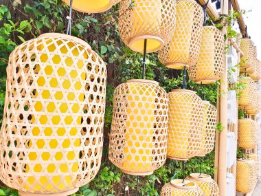 Yeşil yapraklar ve sergilenen Çince karakterlerle çevrili düzinelerce dokuma sarı fener bambu bir çerçeveye asılmış. 