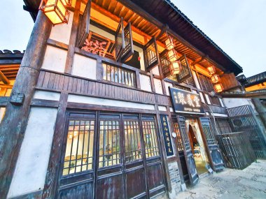 Geleneksel Çin çay evi ahşap mimari, asılı fenerler, açık hava oturma yerleri ve yemyeşil çimlerle çevrili taştan yollar. 