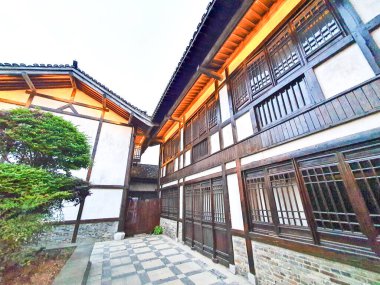 Geleneksel ahşap binalarla çevrili ve yemyeşil ağaçlarla gölgelenmiş sakin bir ara sokakta taş bir patika esiyor. 