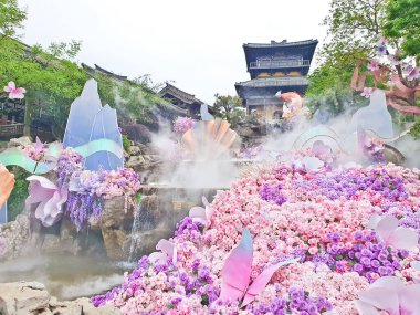 Pastel süslemeli güzel bir çeşme, çağlayan su, ve canlı çiçekler ve sisle çevrili geleneksel bir Asya tapınağı. 