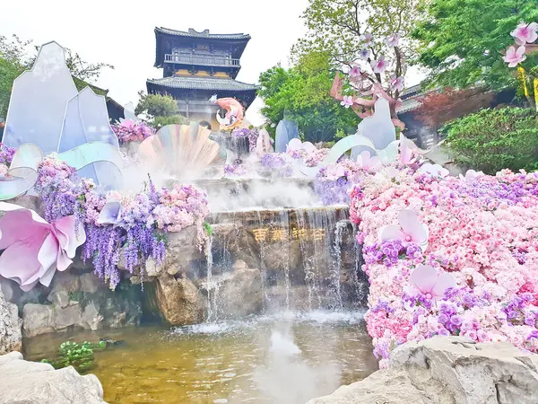 Pastel süslemeli güzel bir çeşme, çağlayan su, ve canlı çiçekler ve sisle çevrili geleneksel bir Asya tapınağı. 