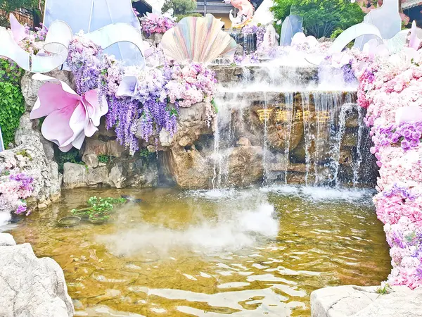 Pastel süslemeli güzel bir çeşme, çağlayan su, ve canlı çiçekler ve sisle çevrili geleneksel bir Asya tapınağı. 