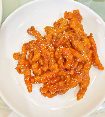 Tatlı ve ekşi domuz pirzolası, zengin bir sosla parlıyor ve susam tohumları serpiştiriliyor. 