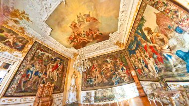 Görkemli, özenle hazırlanmış duvar halıları, boyanmış tavanı ve büyük bir avizesi olan tarihi bir oda. 