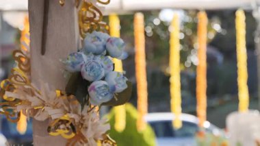 Bir düğün yeri beyaz sütunlar, turuncu ve beyaz çiçekler ve büyük, dekoratif bir haçla süslenir. 