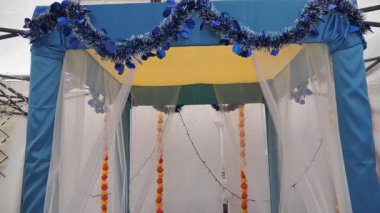 Bir düğün yeri beyaz sütunlar, turuncu ve beyaz çiçekler ve büyük, dekoratif bir haçla süslenir. 