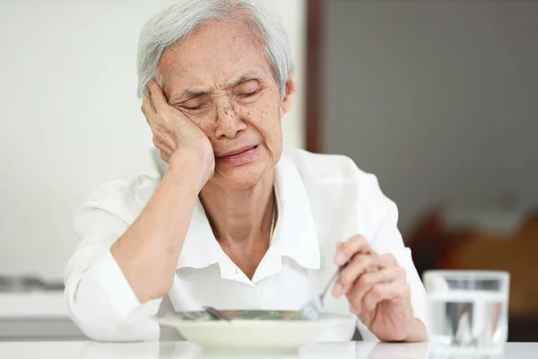 Disappointed old elderly people eating overnight food,she\'s sick of food,tired of eating same food,lacking flavor,Asian senior woman suffering from anorexia,loss of appetite,diet and nutrition concept