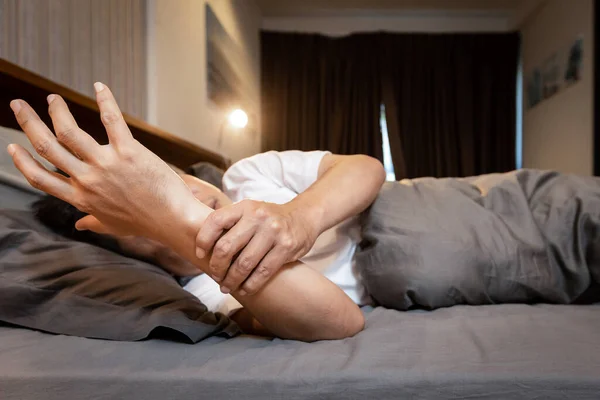 亚洲中年男子生病 患帕金森病 有休息颤抖症状 躺在床上牵手控制手颤抖 健康问题 — 图库照片
