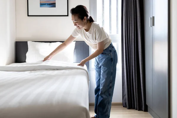 亚洲的年轻女子在床上铺毛毯 在房间里换床 少女开开开心心地微笑着打扫房间 整理卧室 在家里料理家务 做家务活 享受卫生习惯 — 图库照片