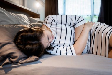 Asyalı orta yaşlı bir kadın karnına dokunuyor, şiddetli karın ağrısı, çikolata kisti, endometriyozis hastalığı belirtileri, pelvik ağrısı olan hasta bir kadın, akut pelvis boşluğu ağrısı, jinekoloji, sağlık konsepti.