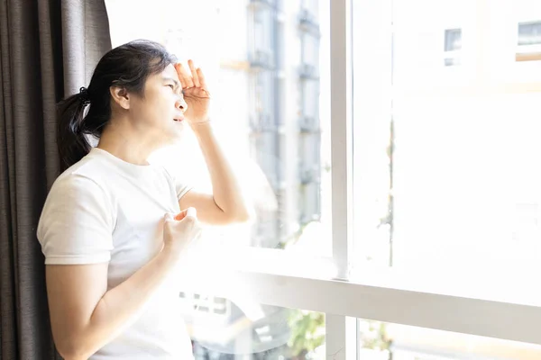 亚洲女人从窗户向外看强烈的阳光 炎热的天气 高温的热浪 强烈的紫外线 眼睛受损的风险 全球变暖 气候变化 厄尔尼诺 医疗保健 — 图库照片