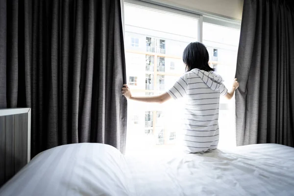 亚洲女青年打开窗帘和窗户进行卫生 阳光照进卧室 室内空气自由流通 减少霉菌 潮湿气味 消除病菌霉菌 卫生观念 — 图库照片