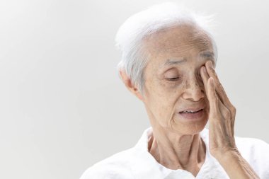 Yaşla ilgili maküler dejenerasyona (AMD) sahip Asya 'lı yaşlı bir kadın, retina ya da göz maskülü dejenerasyonu, bulanık görme, eline dokunan yaşlı bir kadın, görme kaybı, sağlık bakımı, tıbbi bakım