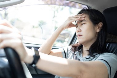 Uykulu Asyalı bir kadının araba sürerken uykuya dalması tehlikeli sürücü davranışı, ilaçlardan kaynaklanan uyuşukluk ya da yetersiz dinlenme, kaza riski, sürüş güvenliği, yol güvenliği.