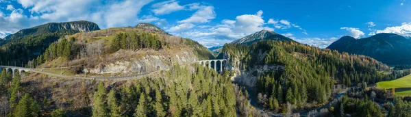 Landwasser Viaduct 'un dünya mirası manzarasının panorama manzarasında İsviçre Alpleri' nde kış günü kar manzaralı lüks Buzul ekspres treni görülüyor. İsviçre 'de panoramik manzaralı demiryolu turizmi.