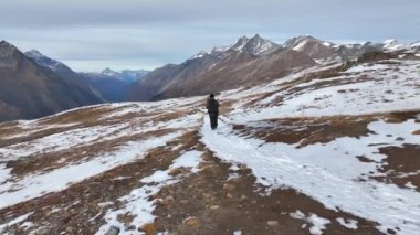 Hava aracı, genç turist yürüyüşçüyü sırt çantasıyla takip ediyor. İsviçre, İsviçre 'de dağın tepesine tırmanan başarılı bir dağcı. Aktif seyahat yaşam tarzı sonbahar açık hava aktiviteleri. Yavaş çekim.