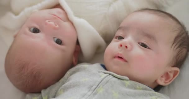 かわいい新生児の双子の男の子と女の子がベッドの中に幸せに笑みを浮かべている 2人の白人の赤ん坊の弟と妹が家の寝室に一緒に横たわっていた 幸せな家族の子供の積極的な子供の就寝時の生活 — ストック動画