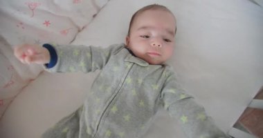 Beyaz, rahat bir yatakta uzanmış, evdeki kameraya bakan sevimli beyaz çocuk. Mutlu aile çocukluğu, pozitif çocuk yatma zamanı yaşam tarzı. Pov portresini kapat.