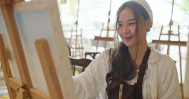Güzel Asyalı stil sahibi kadın sanatçının portresi kollarını kavuşturup kameraya gülerek sanat stüdyosundaki kendine güvenen ve mutlu duygularla bakıyordu. Yaşam tarzı, hobi ve meslek kavramı.