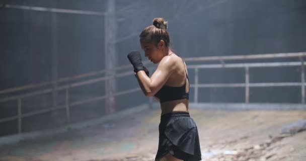 职业女子拳击手在交叉训练练习场练皮拳 年轻的亚洲女战士在废弃的建筑黑暗大厅体育馆里锻炼 练习她的动作 慢动作 — 图库视频影像