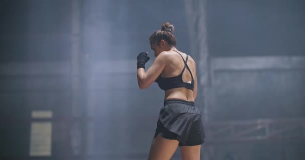 职业女子拳击手在交叉训练练习场练皮拳 年轻的亚洲女战士在废弃的建筑黑暗大厅体育馆里锻炼 练习她的动作 慢动作 — 图库视频影像