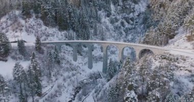 Hava aracı görüntüsü Landwasser Viaduct dünya mirası manzarası lüks Buzul ekspres treniyle İsviçre Alpleri kar günü manzarası. İsviçre 'de panoramik manzaralı demiryolu turizmi.
