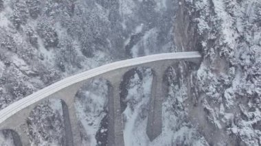 Hava aracı görüntüsü Landwasser Viaduct dünya mirası manzarası lüks Buzul ekspres treniyle İsviçre Alpleri kar günü manzarası. İsviçre 'de panoramik demiryolu manzarası. Kar, Ağır çekim.