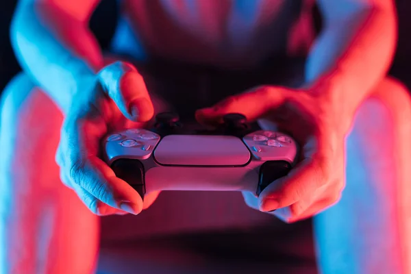 Man hands with game controller in neon light, front view. High quality photo