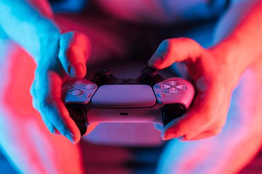 Man hands with game controller in neon light, front view. High quality photo