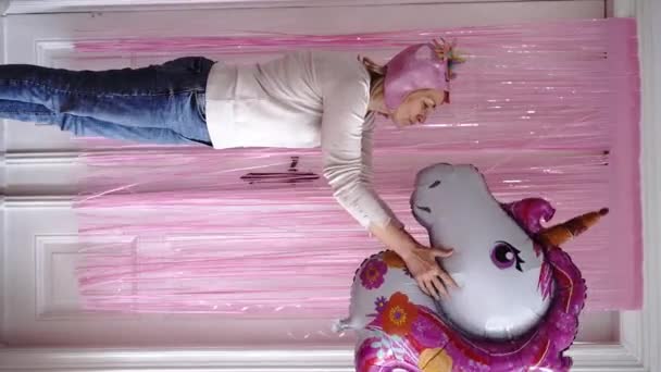 ユニコーンバルーンとピンクのカーテンを持つ熟女は自宅でお祝いします 高品質4K映像 — ストック動画