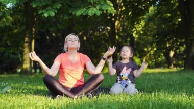 Orta yaşlı, çocuklu bir anne parkta meditasyon yapıyor. Yüksek kalite 4k görüntü