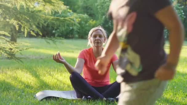 Dojrzała Kobieta Medytuje Świeżym Powietrzu Parku Zachodzie Słońca Biegającym Dzieckiem — Wideo stockowe