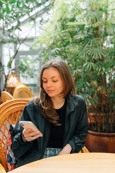 熱帯レストランで電話を使う20歳の女性 高品質の写真 — ストック写真