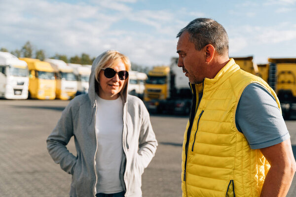 Mature woman and man at cargo warehouse, truck drivers delivery partners. High quality photo