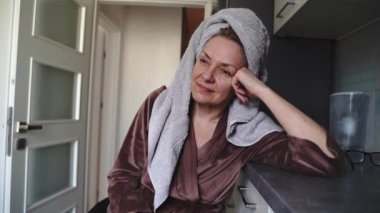 Kadife bornoz ve havlu giymiş olgun bir kadın kendini kötü hissediyor. Akşamdan kalma ya da hasta gibi hissediyorum. Yüksek kalite fotoğraf