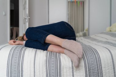 Olgun bir kadın, ev manzarasında yatağa kıvrılmış yatıyor. Depresyon, akıl sağlığı, istismar sorunu. Yüksek kalite fotoğraf