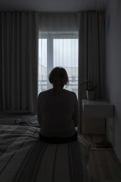 Mature woman sitting alone in the room, sad depressed person. Back view. mental health problemageing population. High quality photo