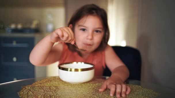 子供の女の子は自宅でボウルからスプーンで食べる そうだ 高品質の写真 — ストック動画