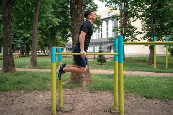Middle age adult man doing outdoors workout on bars in park, healthy active lifestyle . High quality photo
