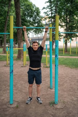 Orta yaşlı bir adam açık hava idman alanında barfiks çekiyor. Yüksek kalite fotoğraf