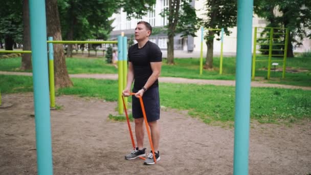 公園の屋外で抵抗バンドと強い練習をしている中年男性 高品質の写真 — ストック動画