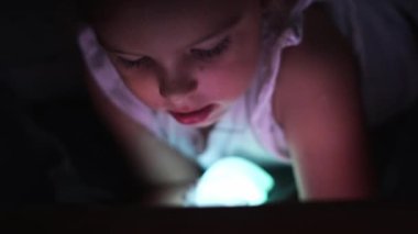 Çocuk kız çizgi film ya da sosyal medya izliyor ya da gece tablette oyun oynuyor. Gözler ekrana çok yakın. Kötü alışkanlık, uykusuzluk sorunu. Yüksek kalite 4k görüntü