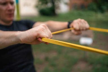 Orta yaşlı bir adam parkta direniş bantlarıyla güç egzersizleri yapıyor. Yüksek kalite fotoğraf
